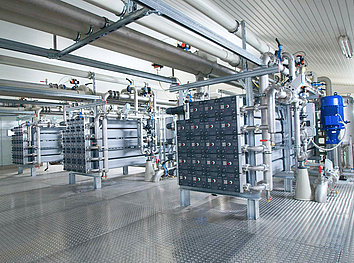 Stainless steel pipelines with blue flange valves and large black handwheels in a water treatment plant.