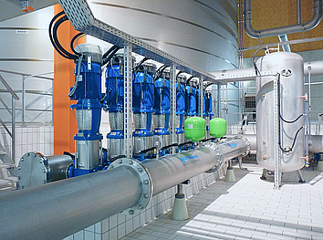 Industrial stainless steel tank with ozone system, blue centrifugal pump, and piping on conical machine feet.