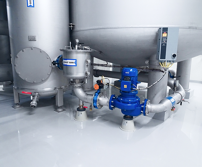 Multi-stage vertical centrifugal pumps in blue on stainless steel piping with adjustable pipe supports in an industrial plant.